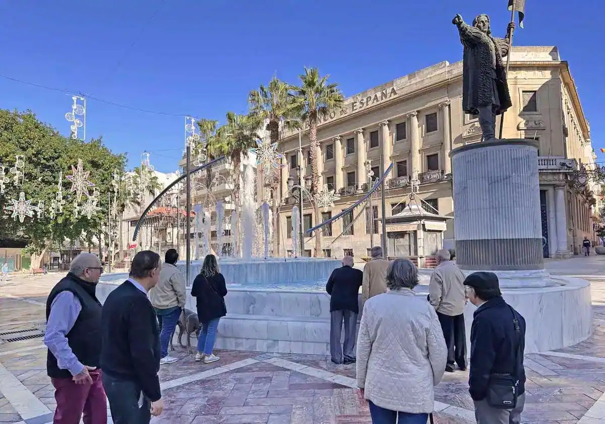 Viandantes observan la fuente de la plaza de las Monjas en Huelva